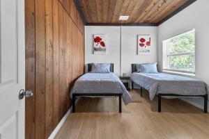 two beds in a room with wood paneling at 4 Bedroom Modern Luxe Retreat with Hot Tub 5 Mins to Beach in West Palm Beach