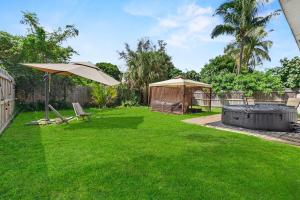 a lawn with an umbrella and a chair and a table at 4 Bedroom Modern Luxe Retreat with Hot Tub 5 Mins to Beach in West Palm Beach