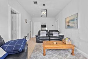 a living room with a leather couch and a coffee table at 4 Bedroom Modern Luxe Retreat with Hot Tub 5 Mins to Beach in West Palm Beach