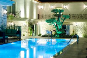 una piscina en un hotel con un árbol en el fondo en Alaçatı The Design Hotel, en Alacati