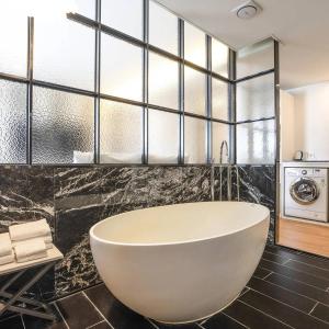 a bath tub in a bathroom with black tiles at Hotel Circle Yonghyeon in Incheon +21 photos