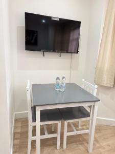 a white table with two chairs and a tv on a wall at Shelters En-suite Entire House in Seven Kings
