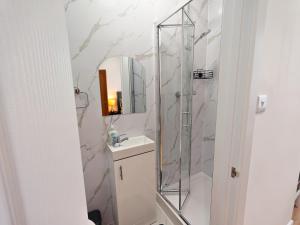 a bathroom with a shower and a sink and a mirror at Shelters En-suite Entire House in Seven Kings +32 photos