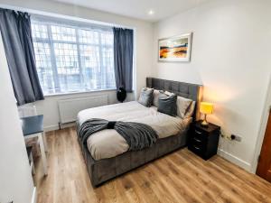 a bedroom with a bed and a large window at Shelters En-suite Entire House in Seven Kings