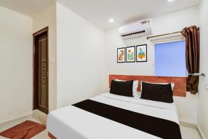 a bedroom with a white bed with black pillows at Collection O Neredmet Road in Hyderabad