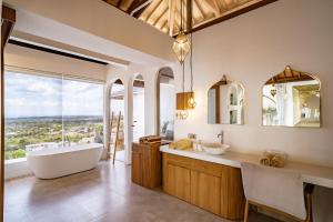 a bathroom with a tub and a sink and mirror at La Concha Bingin in Bingin Beach