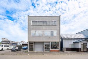 a tall building with cars parked in a parking lot at SnowGarden YIG STAY in Furano