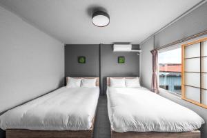 two beds in a room with a window at SnowGarden YIG STAY in Furano