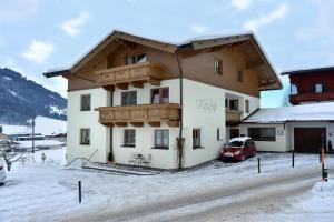 a house in the snow with a car parked in front at Landhaus KitzAlp (Alpenheim) in Brixen im Thale