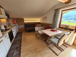 a kitchen and a living room with a table and a kitchen and a couch at Landhaus KitzAlp (Alpenheim) in Brixen im Thale