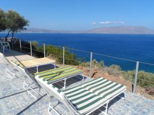 - deux chaises longues et une table avec vue sur l'océan dans l'établissement Michalis Holiday Home, à Ravdhoúkha