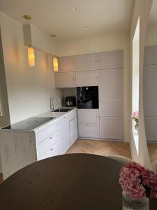 a kitchen with white cabinets and a black counter top at Strøken og ærverdig bygårdsleilighet ved Bergen Domkirke in Bergen +5 photos