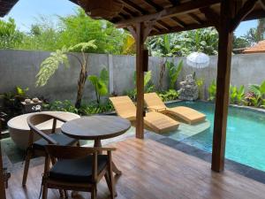 a patio with a table and chairs and a swimming pool at Yana Villas Kemenuh by GenuineHost in Ubud