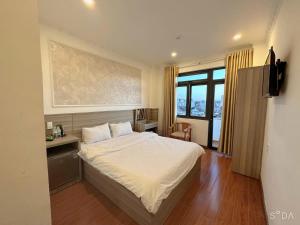 a bedroom with a bed and a desk and window at Lina Hotel in Khu Chi Lăng