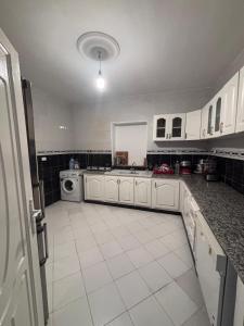 a large kitchen with white cabinets and a tile floor at Cottage with swimming pool in Borj el Khessous