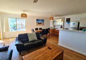 a living room with a black couch and a kitchen at Sandcastles Beachfront Luxury Retreat Apartment in Perth