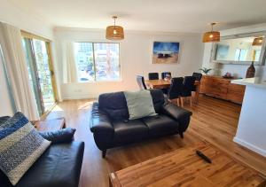 a living room with a leather couch and a table at Sandcastles Beachfront Luxury Retreat Apartment in Perth