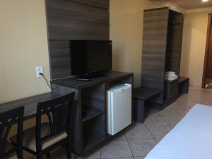 a living room with a tv and a table with chairs at Inácio Palace Hotel in Rio Branco