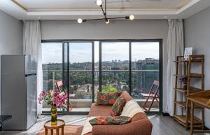 een woonkamer met een bank en een groot raam bij Escada Studio & 2-bedroom, Rooftop Swimming Pool, Gym, Workspace, Wonderiss Homes Westland Living in Nairobi