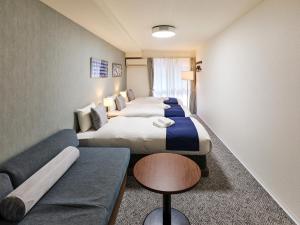 a hotel room with two beds and a couch at &haku Kyoto Marutamachi in Kyoto