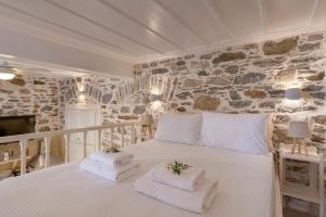 a bedroom with a white bed and a stone wall at Vaporia seaview suites - Balcony suite in Ermoupoli