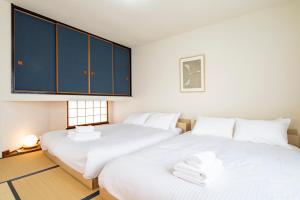 Dos camas en una habitación con sábanas blancas y armarios azules. en Tsubaki オーシャンビュー 観光拠点 閑静な住宅街, en Otaru