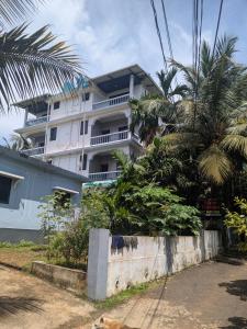 Un edificio blanco con palmeras delante. en Shivkrupa Apartments, en Arambol