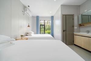 two beds in a room with a kitchen and a sink at Qiyunju Hotel-24H Free Airport Pickup Drop-off in Shanghai