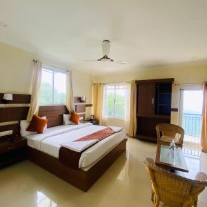 a bedroom with a bed and a table and windows at Casa Nube Resort Munnar in Munnar