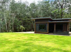 クラビタウンにあるYour Red Earth Homestayの前に緑の芝生がある小屋