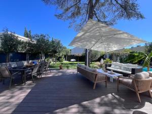 eine Terrasse mit Tischen und Stühlen und einem Sonnenschirm in der Unterkunft Superbe villa avec piscine in Castelnau-le-Lez