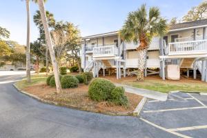 a apartment building with palm trees and a parking lot at Lagoon Villa 43 - Close to Ocean! Easy Access to Resort! in Isle of Palms