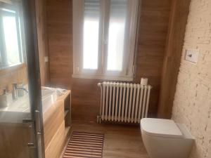 a bathroom with a toilet and a sink and a window at Affittacamere D&B in Pogliano Milanese