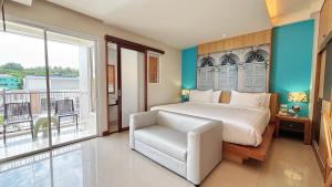a bedroom with a bed and a chair and a balcony at Ratana Hotel Rassada, PHUKET TOWN- SHA Extra Plus in Phuket Town