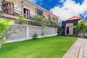 einen Garten vor einem Haus mit einem Zaun in der Unterkunft Collection O Bali Sanur near Bali Mandara Hospital in Sanur