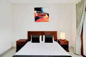 ein Schlafzimmer mit einem Bett mit weißen Laken und einem Gemälde in der Unterkunft Collection O Bali Sanur near Bali Mandara Hospital in Sanur