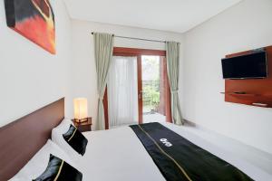 ein Hotelzimmer mit einem Bett und einem Fernseher in der Unterkunft Collection O Bali Sanur near Bali Mandara Hospital in Sanur