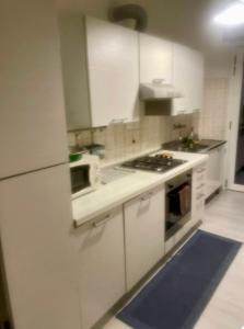 a kitchen with white cabinets and a stove top oven at Affittacamere D&B in Pogliano Milanese