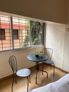 een tafel en twee stoelen in een kamer met twee ramen bij OffDuty Hostel Koregaon Park in Pune +32 foto's