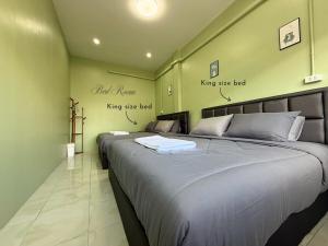 Dos camas en una habitación con paredes verdes. en O Pha Suk House, en Hat Yai