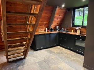 a kitchen with black cabinets and a wooden staircase at Chalet AbA, proche Luchon in Cierp