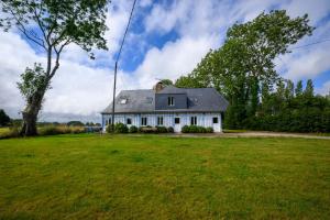 a white house with a tree and a grass field at Blue cottage in Normandie in Ouville-lʼAbbaye