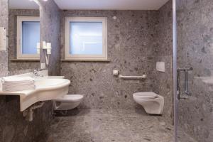 a bathroom with a sink and a toilet and a shower at Aparthotel Familiaris - Family Apartments - Pools & Spa in Dolomites in Valdaora +215 photos