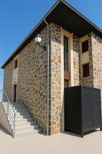a building with a stone wall and a staircase at Albergue Pundak Valle del Jerte in Cabezuela del Valle