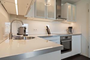 ヴァーレンにあるFirst Marina View - Apartment in der Hafenresidenz mit Sauna & Müritzblickの白いキャビネットとシンクのあるキッチン