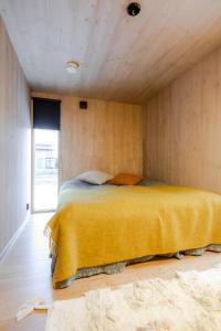 a bedroom with a bed with a yellow blanket at Moderni puuhuvila erämaan reunalla Kiilopäällä in Saariselka