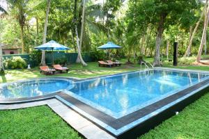 una piscina en un patio con sombrillas en Asnaka Villa, en Nikawatawana
