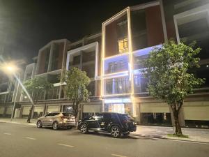 two cars parked in front of a building at night at Grand Central Hotel- Vinhomes Ocean Park 3 in Ðình Loan