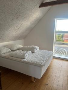 a white bed in a room with a large window at Katelenas Bed & Breakfast in Glesborg