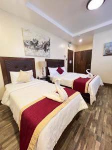 a hotel room with two beds with swans on them at Hotel Maefinn in Bayawan